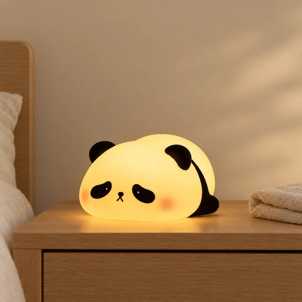 Veilleuse panda en silicone tactile et rechargeable allumée sur une table de chevet en chêne dans une chambre d’enfant