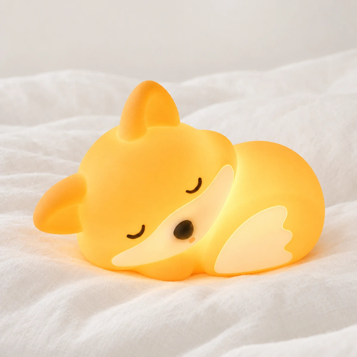 Veilleuse renard bébé rechargeable en silicone en gros plan sur un drap blanc